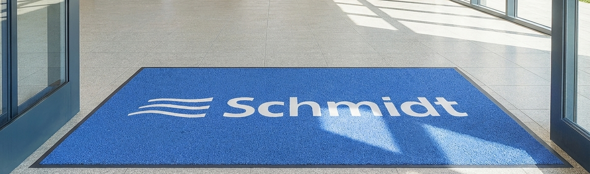 Logo-Matte mit der Aufschrift Schmidt Services in Blau im Eingang eines Bürogebäudes